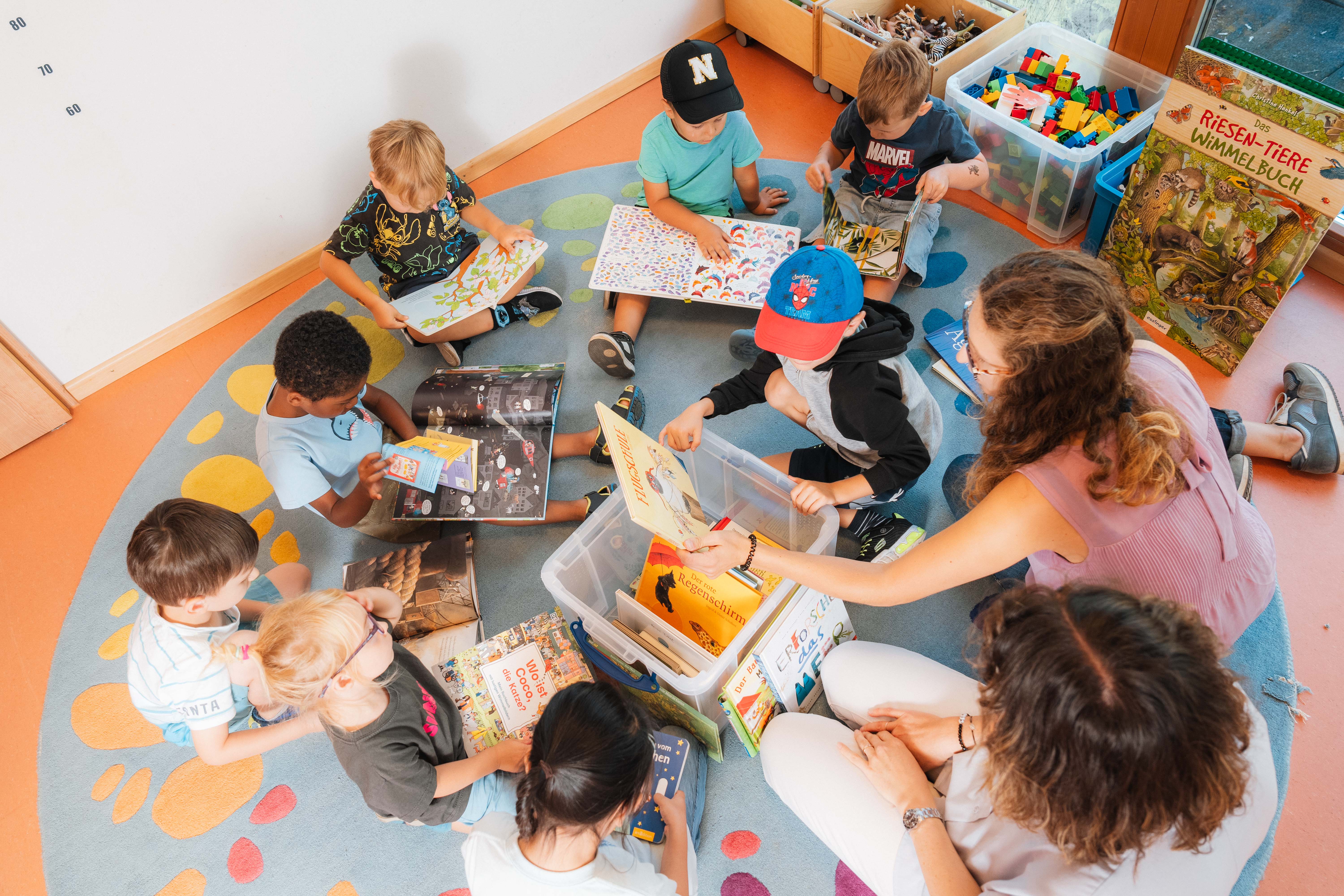 Kinder sitzen auf dem Boden uns schauen Bücher an