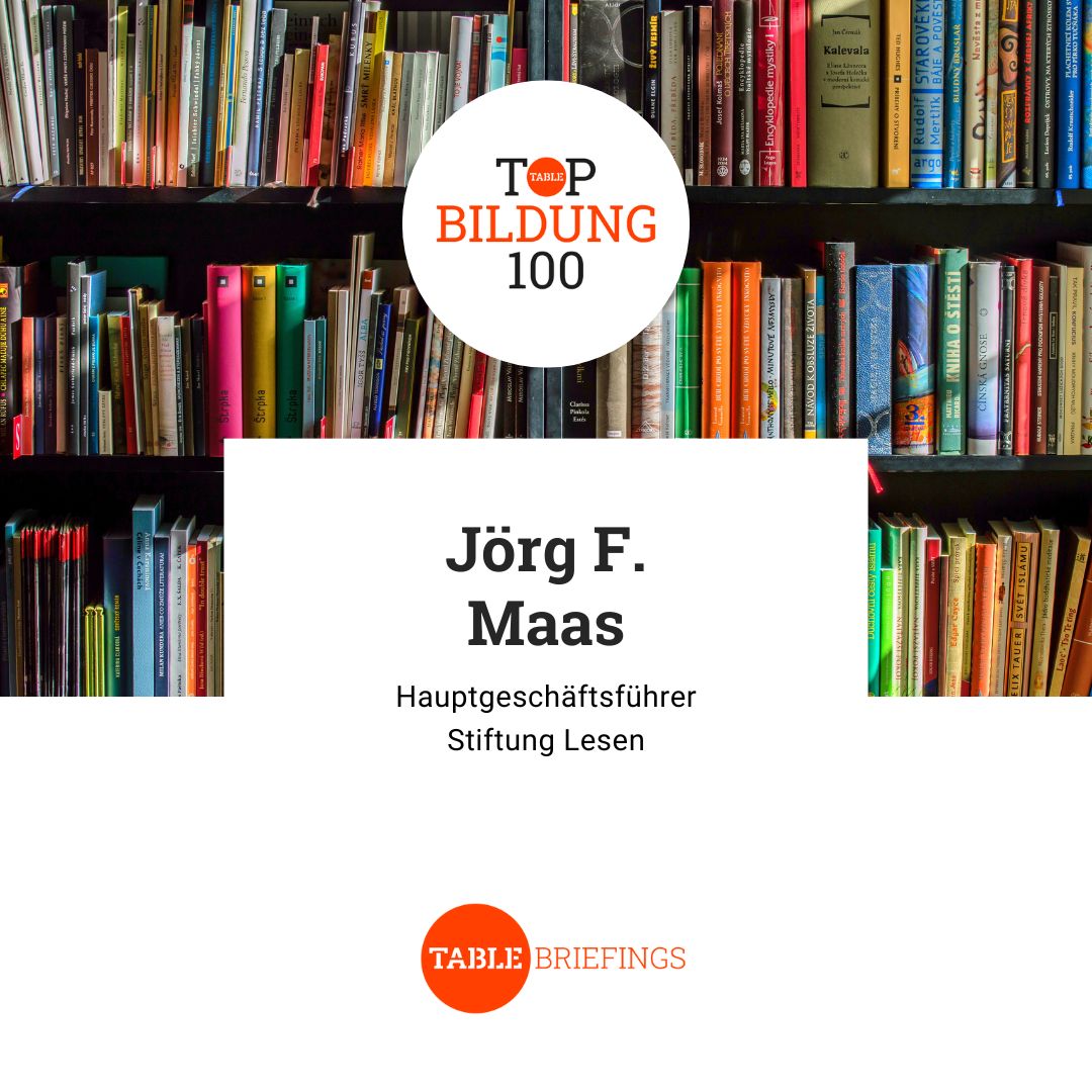 Vor einem Bücherregal steht auf einer Textkachel: Top Bildung 100. Jörg F. Maas. Hauptgeschäftsführer Stiftung Lesen