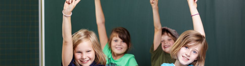 vier Kinder vor einer Tafel melden sich