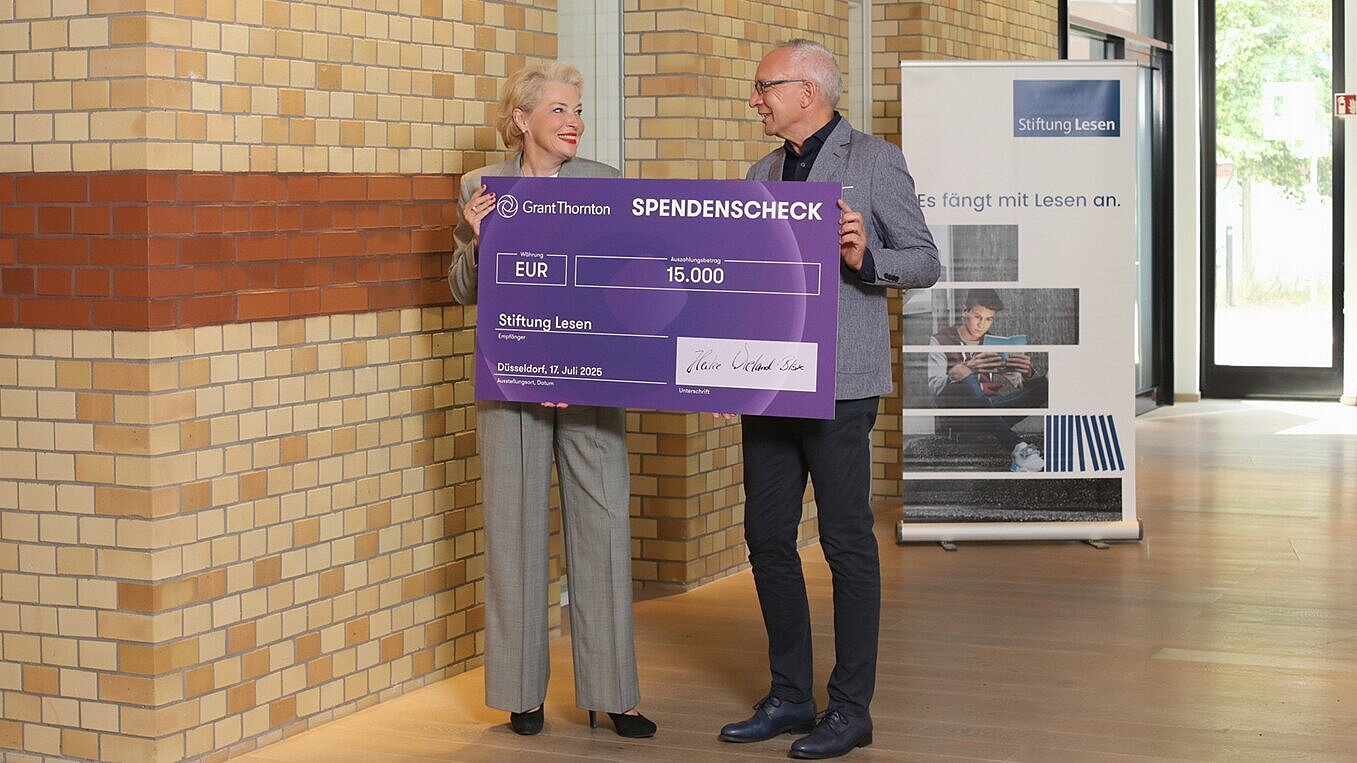 Grant Thornton Deutschland spendet an die Stiftung Lesen  Prof. Dr. Heike Wieland-Blöse, CEO Grant Thornton in Deutschland, steht mit Dr. Jörg F. Maas, Hauptgeschäftsführer der Stiftung Lesen, in einem modernen Gebäude. Sie halten gemeinsam einen übergroßen Spendenscheck über 15.000 Euro mit dem Logo von Grant Thornton Deutschland. Der Scheck ist an die Stiftung Lesen adressiert.