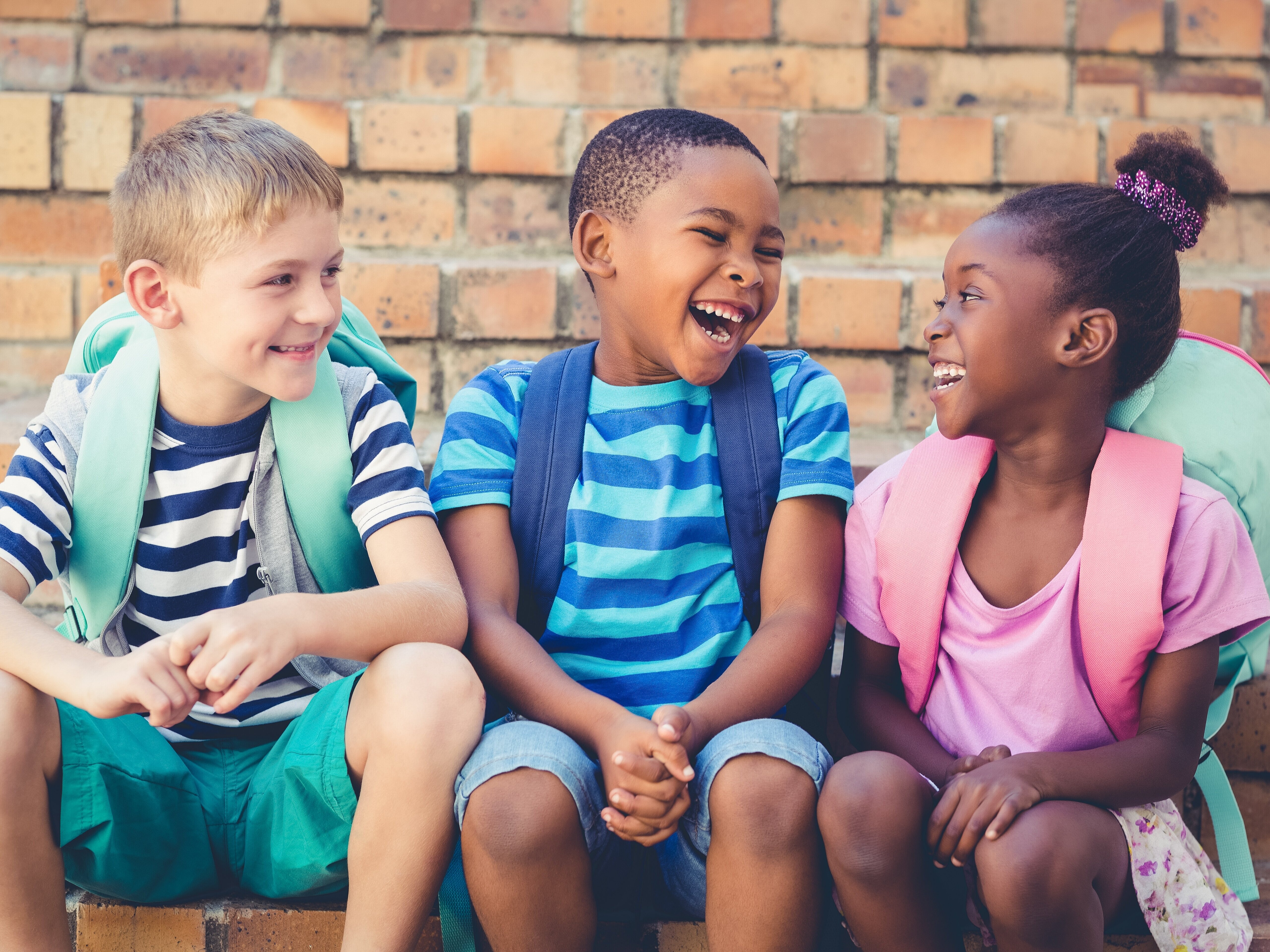 Drei Kinder lachen gemeinsam